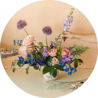 Two hands putting flowers in a vase
