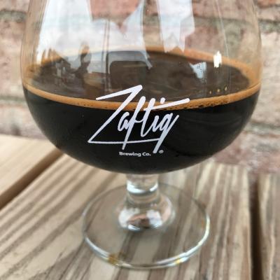 Dark beer in snifter glass printed with Zaftig Brewing logo