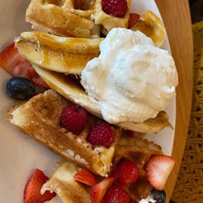 A dollop of cream tops a stack of pancakes covered in sliced banana and berries from Union and Finch