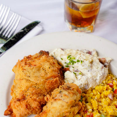 Fried chicken on a plate with mashed potatoes and a cocktail