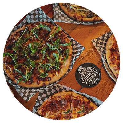 A table with four pizzas and a coaster waiting for a beer