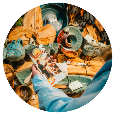 A shopper holding the Cheese Trail brochure with Canadian made pottery in the background
