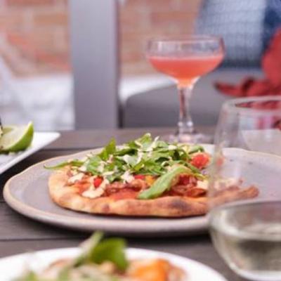 A photo of a small pizza and a cocktail in the background