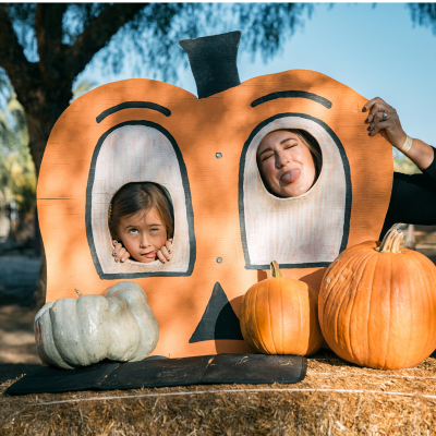 mother and daughter making funny faces in pumpkin face photo opp