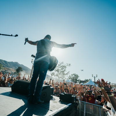 Lead singer with guitar facing audience outdoors