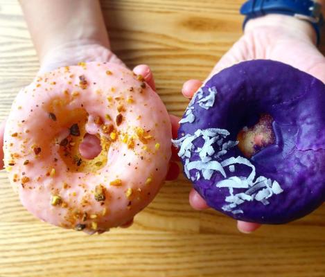 pink and purple donut with two hands holding them