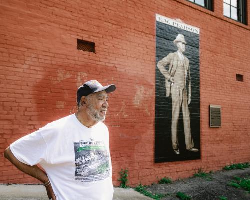 Man standing in front of mural of EW Pearson in West Asheville
