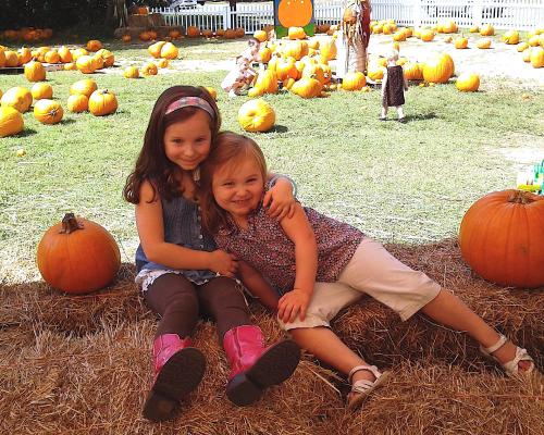 Two young girls hugging in a pumpkin patch
