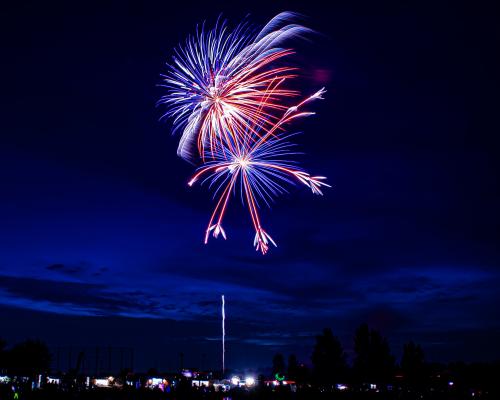 Red and blue fireworks in the dark blue sky during the 4th of July celebration