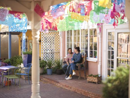 A couple sits on a bench outside a shop in Old Town Albuquerque