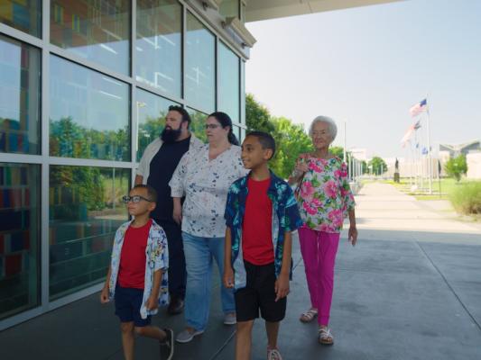 Multi-Generational family visiting Fayetteville's Veterans' Park with the ASOM in the background