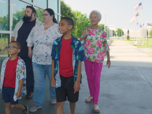 Multi-Generational family visiting Fayetteville's Veterans' Park with the ASOM in the background