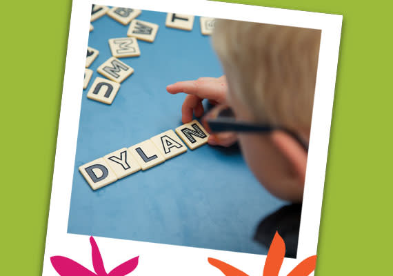 A child spelling out 'Dylan' with letter tiles.