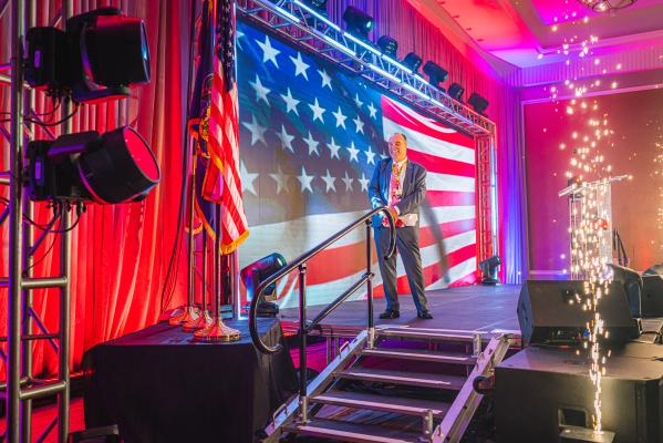 Mike Bowman standing in front of the American Flag at VFTCB's Annual Luncheon