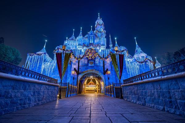 Image of Sleeping Beauty's Castle at Disneyland light up at night. Ice and snow can be seen adorning the castle.