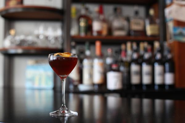 A deep purple cocktail sits on a bar.