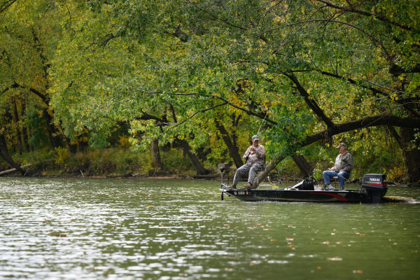 Two people fishing from a boat along a tree lined shoreline at Charlestown State Park in Southern Indiana.