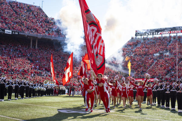 Ohio state cheerleaders and band enter Ohio Stadium during football game.