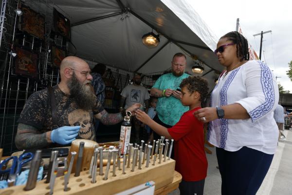 An artist showing his work to a family at Columbus Arts festival.
