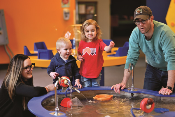 Mother, father and two young kids playing with water experience at COSI