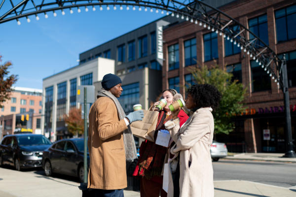 Three people bundled for winter, drinking hot chocolate in the Short North Arts District
