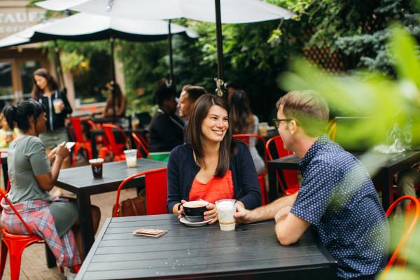 Man and woman sipping coffee outdoors on Stauf's patio