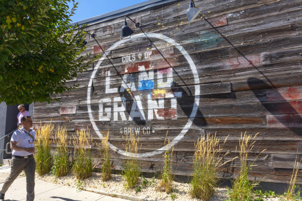 Event attendee walks past the Land-Grant mural outside the brewery facility
