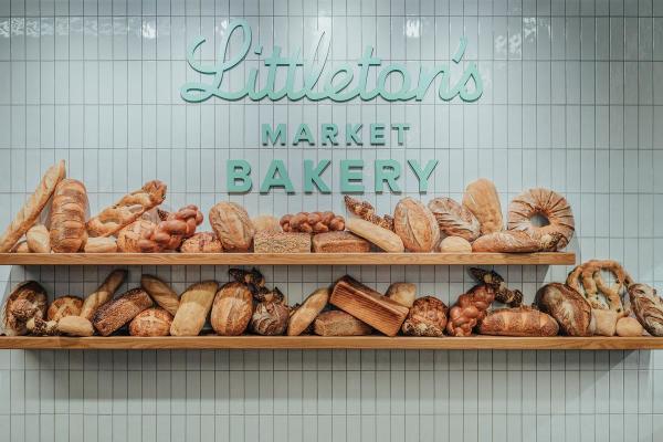A picture of the sign at Littleton's Market Bakery with two shelves full of baked goods underneath.