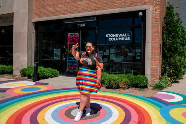 A women holding up a peace sign in front of Stonewall Columbus.