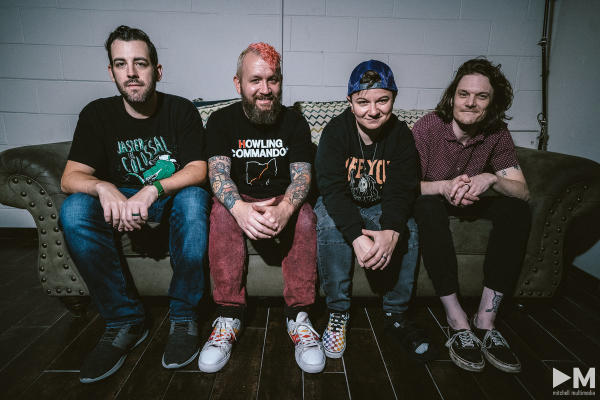The Scratches, an LGBTQ+ Band, sitting on a couch.