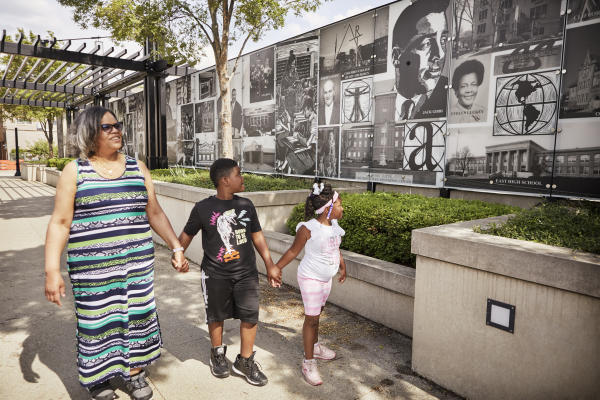 Black family of three walking by Long Street Cultural Wall in Columbus