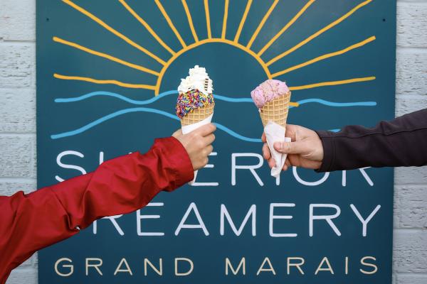 Two people hold ice cream cones at Superior Creamery