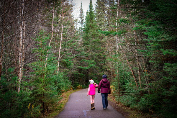 A mom and her daughter walking along a wooded path