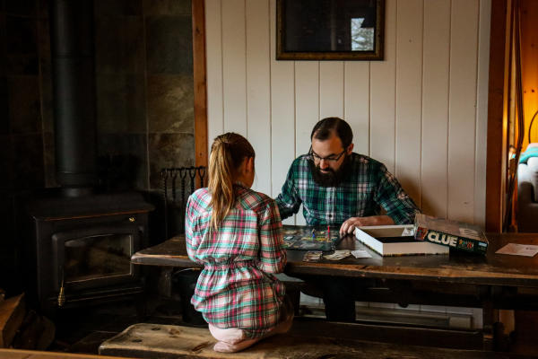 A father plays a game in a cabin with his daughter