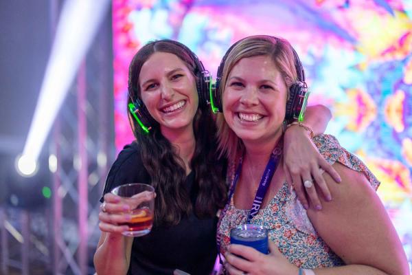 Two women wearing headphones at an event.