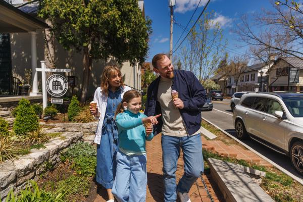 A smiling family enjoys ice cream while strolling past the Dublin Historical Society Museum on a sunny day in Historic Dublin, Ohio.