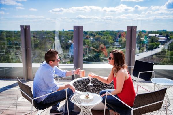 A couple sitting on the VASO rooftop cheersing cocktails while overlooking Downtown Dublin