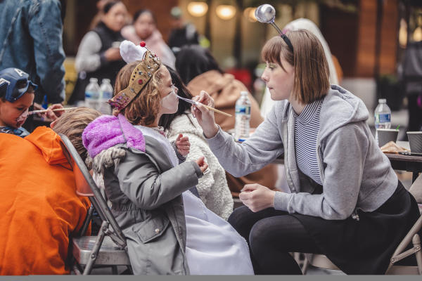Child getting their face painted by a woman at Boo + Brew in Bridge Park