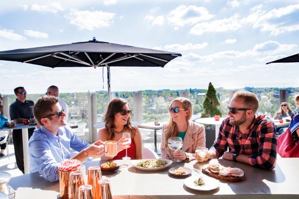 A group of friends enjoying cocktails and appetizers on the rooftop patio at VASO on a sunny day.