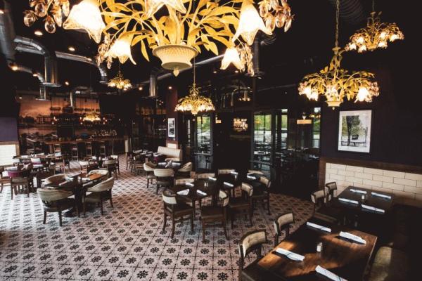 Fado Pub & Kitchen's spacious restaurant with ornate chandeliers, patterned tile floors, wooden tables, and upholstered chairs in a cozy, stylish setting in Bridge Park.