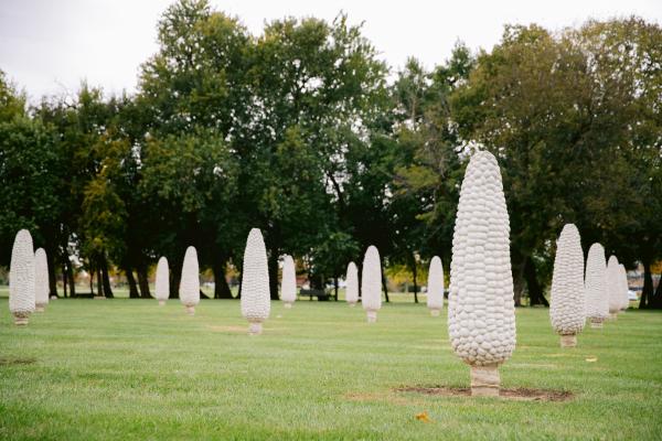 Rows of giant concrete corn sculptures in a field