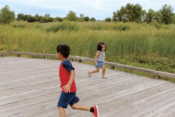 Two kids running around each other on the boardwalk at Glacier Ridge Metro Park