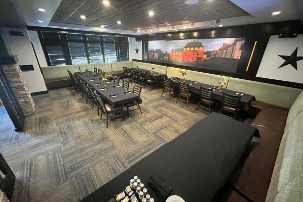 Matt the Miller's Private dining room with black covered tables, booth seating, and a mural, offering a casual and comfortable atmosphere.