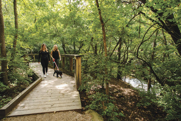 Two girls walking a dog on the path at Indian Run Falls