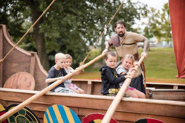 Kids rowing a Viking shop replica with a man dressed in period costume at the Dublin Irish Festival