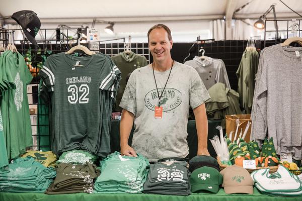 Man standing at his booth at the Dublin Irish Festival selling Ireland apparel