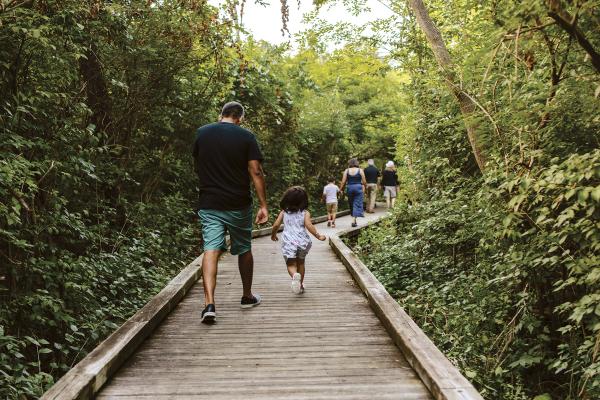 A family running down the boardwalk at Kiwanis Riverway Park