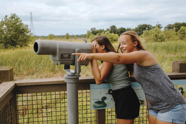 Two teenage girls looking through the telescope at Glacier Ridge Wetlands
