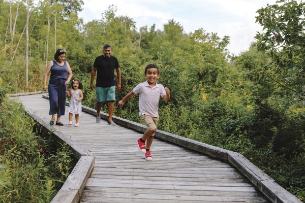 Kid running in front of his family on the boardwalk at Kiwanis Riverway Park
