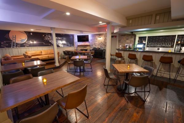 North High Brewing's downstairs private dining room with a cozy, dimly lit room with wooden tables, leather chairs, and a fireplace.